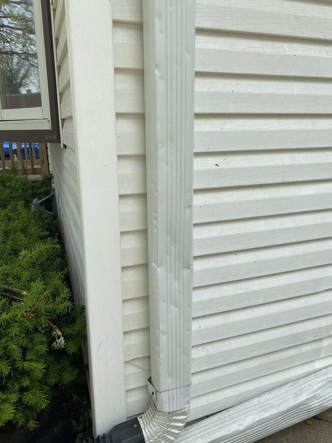 Hail dents on downspout and vinyl siding on residential home