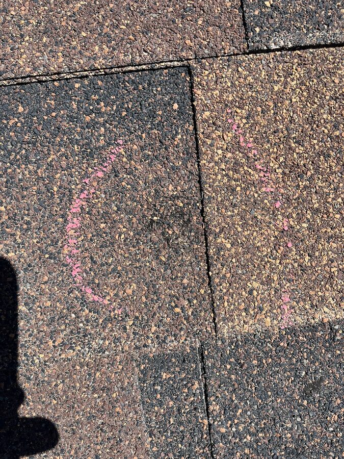 Hail damage marked with chalk circles during roof assessment in Omaha